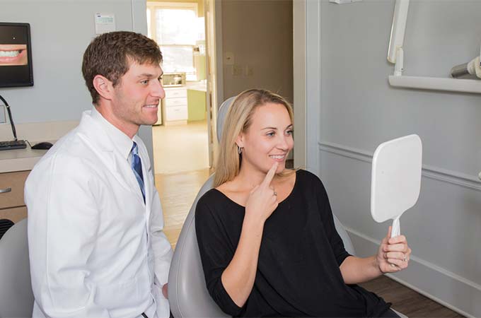 dr Adam Koplon with a patient holding up a mirror during a check up at Koplon Family Dentistry